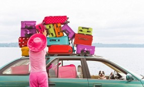 Woman adjusting stack of colorful suitcases on top of car. Image shot 2008. Exact date unknown.